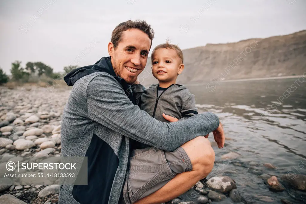 Dad and toddler hugging by yellowstone river on a nature walk