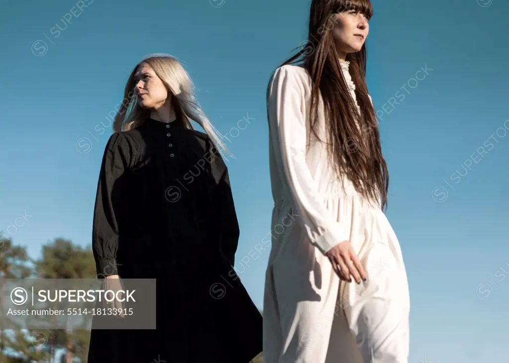 two beautiful twin girls doing style lying in a field at sunset