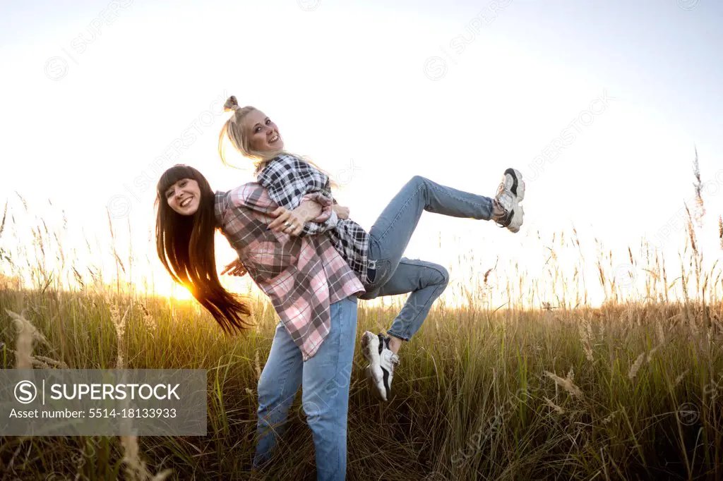 two beautiful twin girls make style in the field at sunset