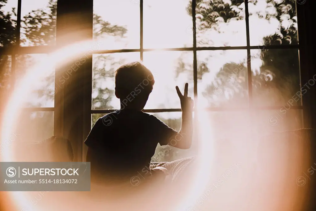 Back of Young Boy in Window Making Peace Sign With Circle Light Effect