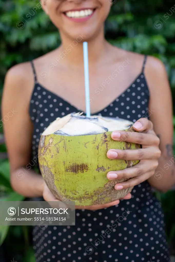 Young woman smiling holding fresh coconut