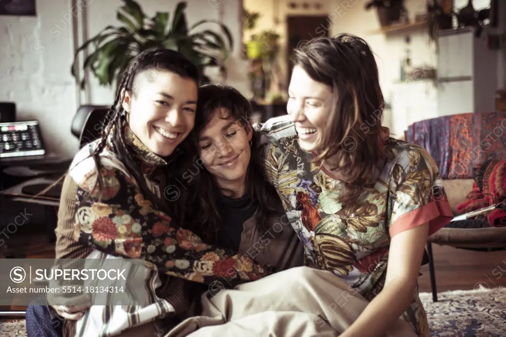 Young alternative female women friends laugh, smile and hug at home