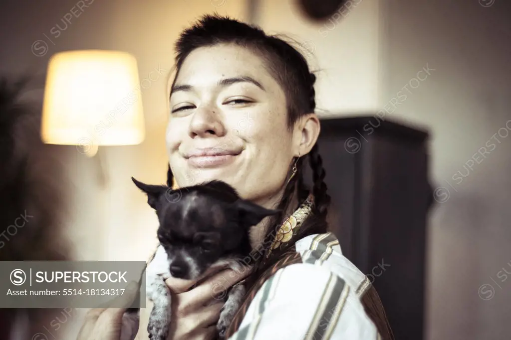 Smiling alternative young queer person with tiny small chihuahua pup