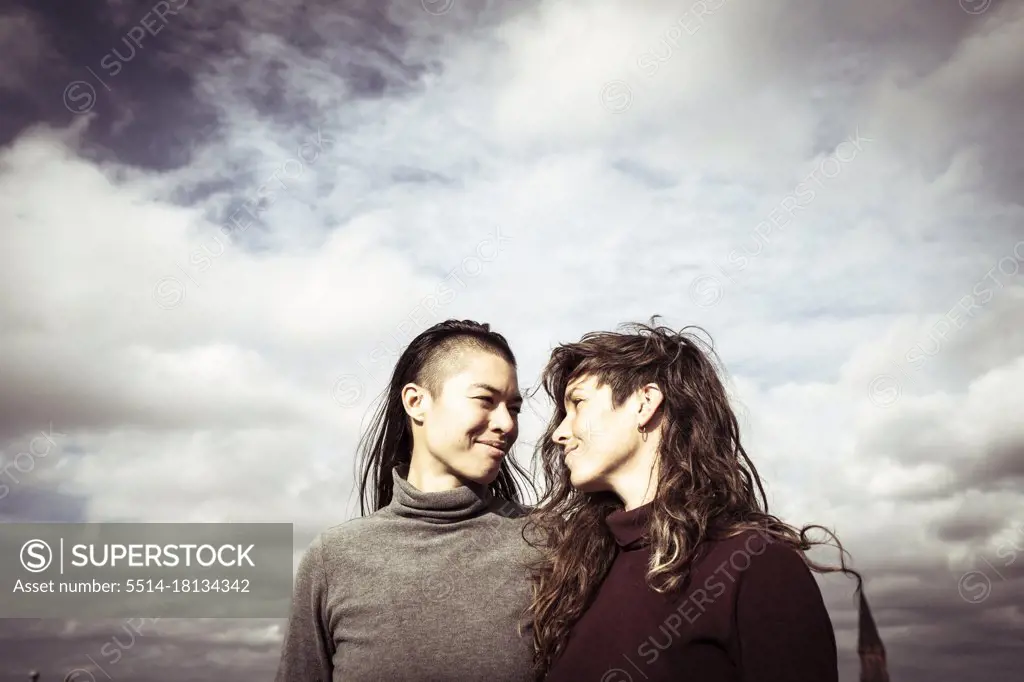 proud queer lesbian couple stand on rooftop with sky above in berlin