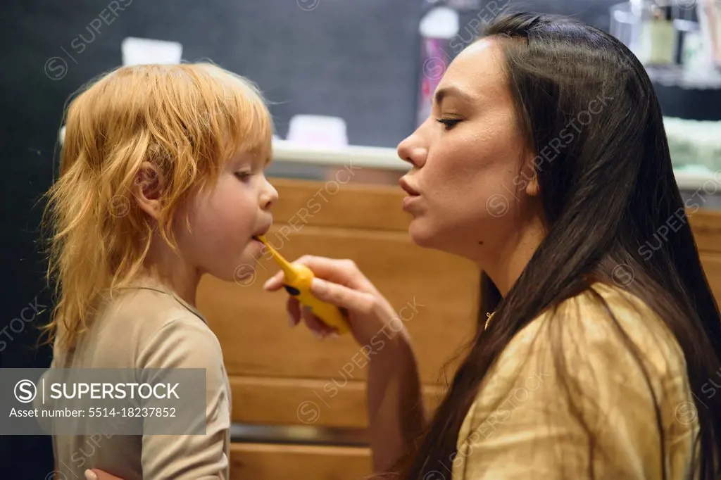 mom teaches her son to brush his teeth. In bathroom.