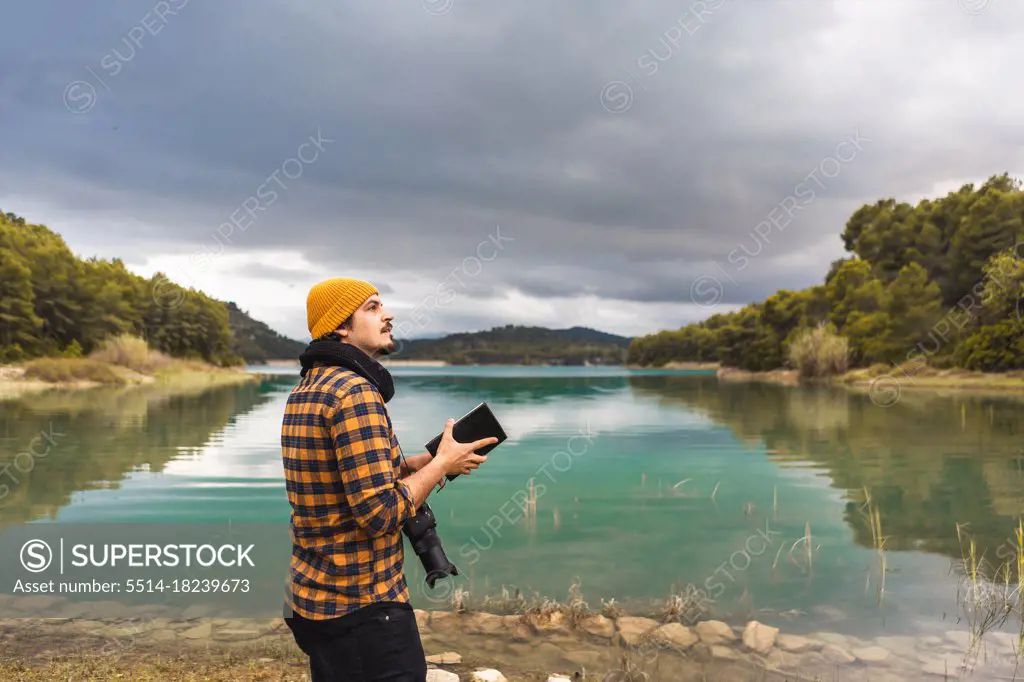 Tourist guide cheking guide book with hat and camera in the lake