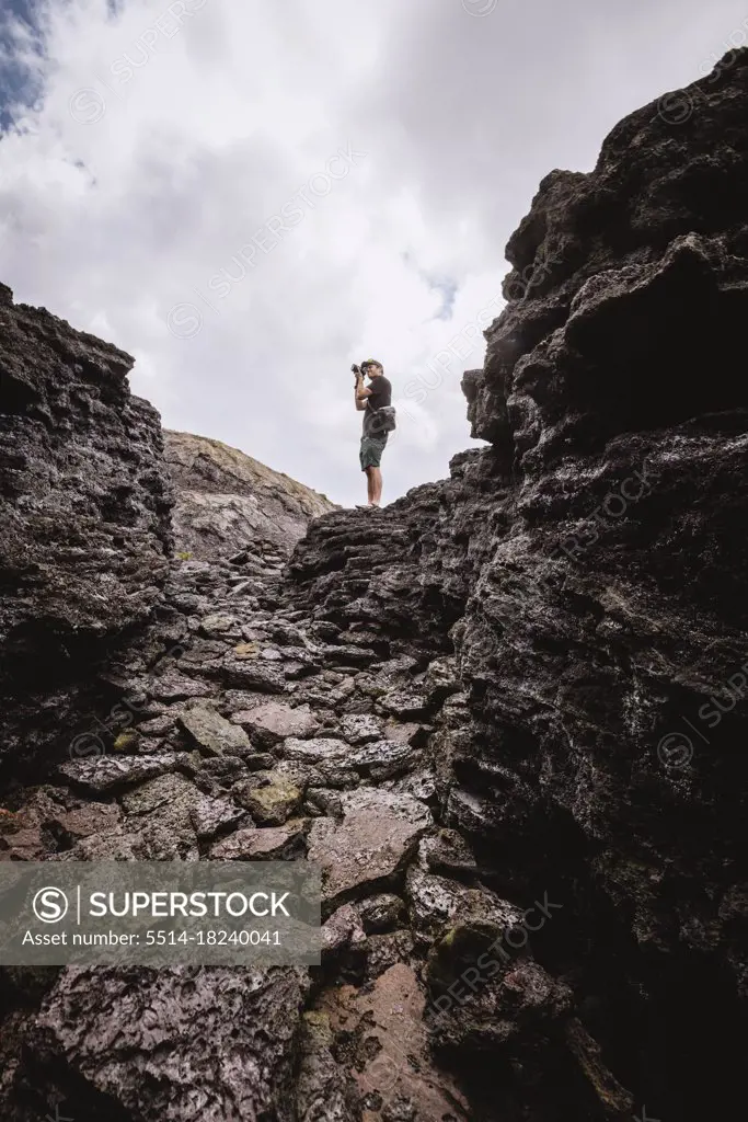 man takes picture among rocks of Hawaii Volcano National Park