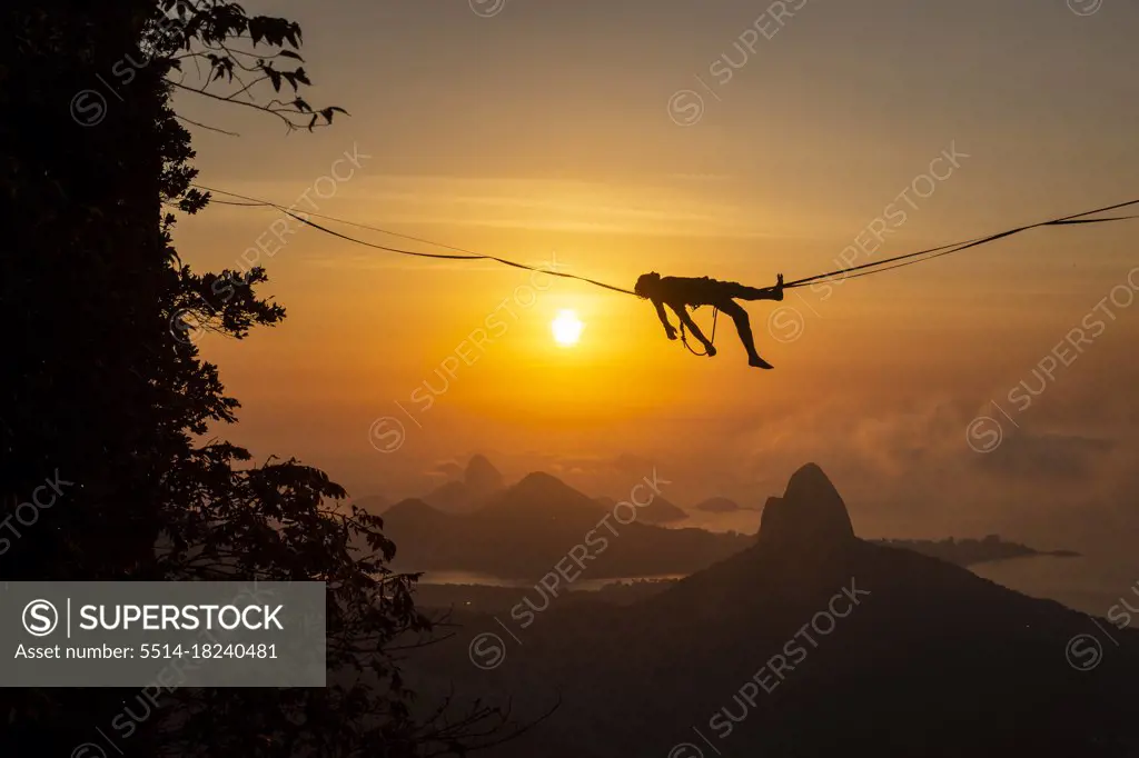 Beautiful view to male highliner silhouette laying down on mountain