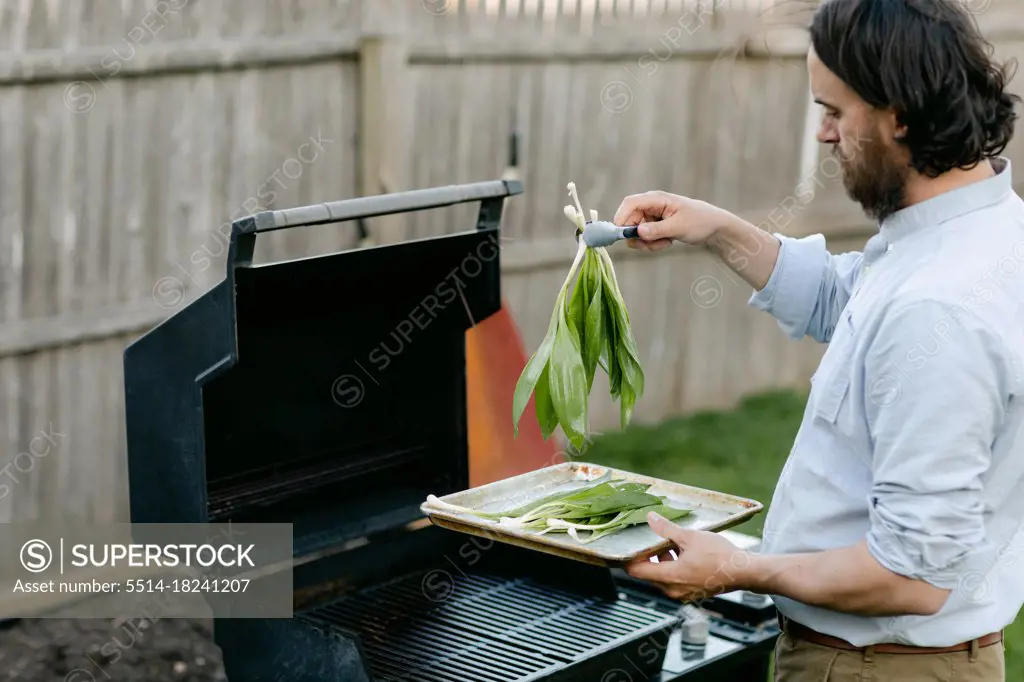 Home cook picking up wild ramps with tongs