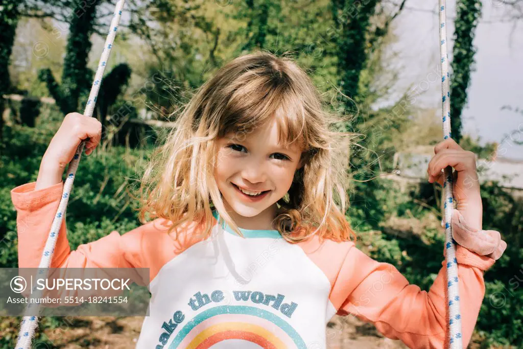 girl sat on a swing in a beautiful garden in the English countryside