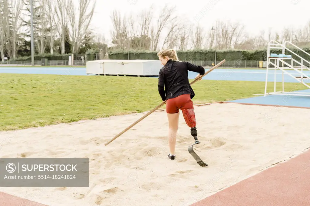 Handicapped sportswoman preparing sand on stadium