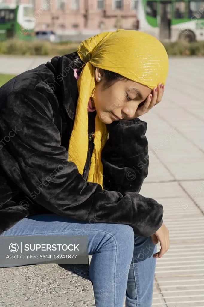 Young woman with cancer undergoing treatment. Disappointment and sadness for the bad news. Wear a yellow bandana or scarf to cover up the effects of chemotherapy.