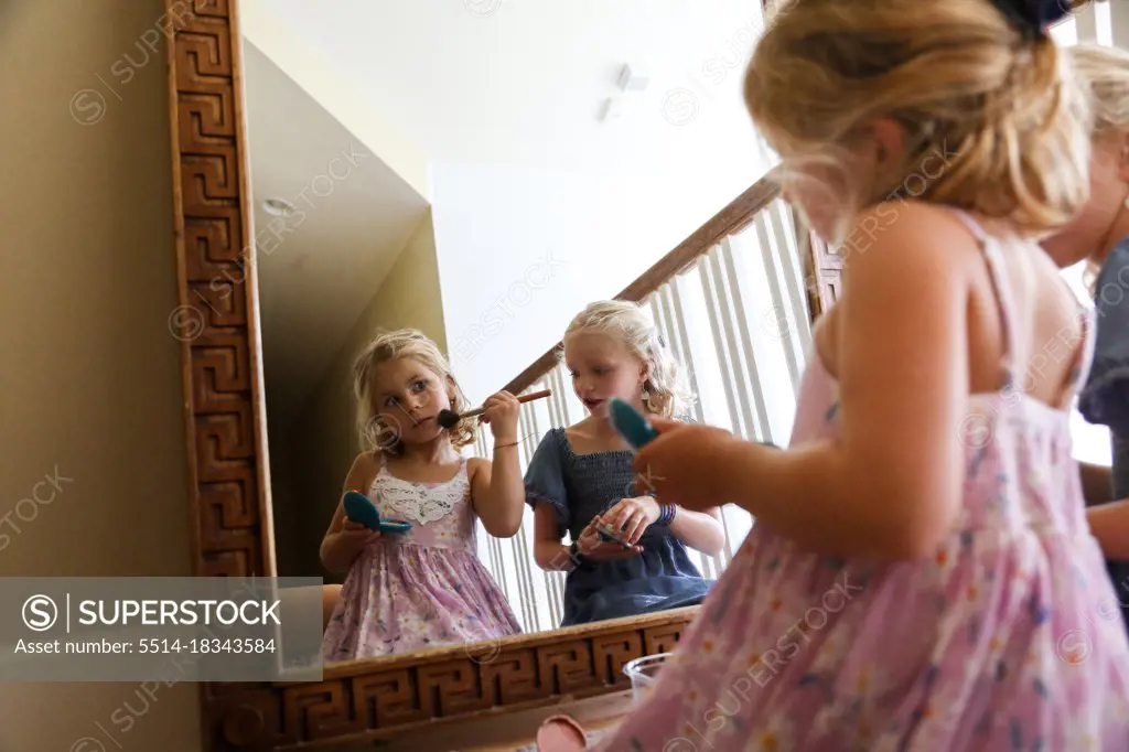 little girl look at herself in mirror putting on blush