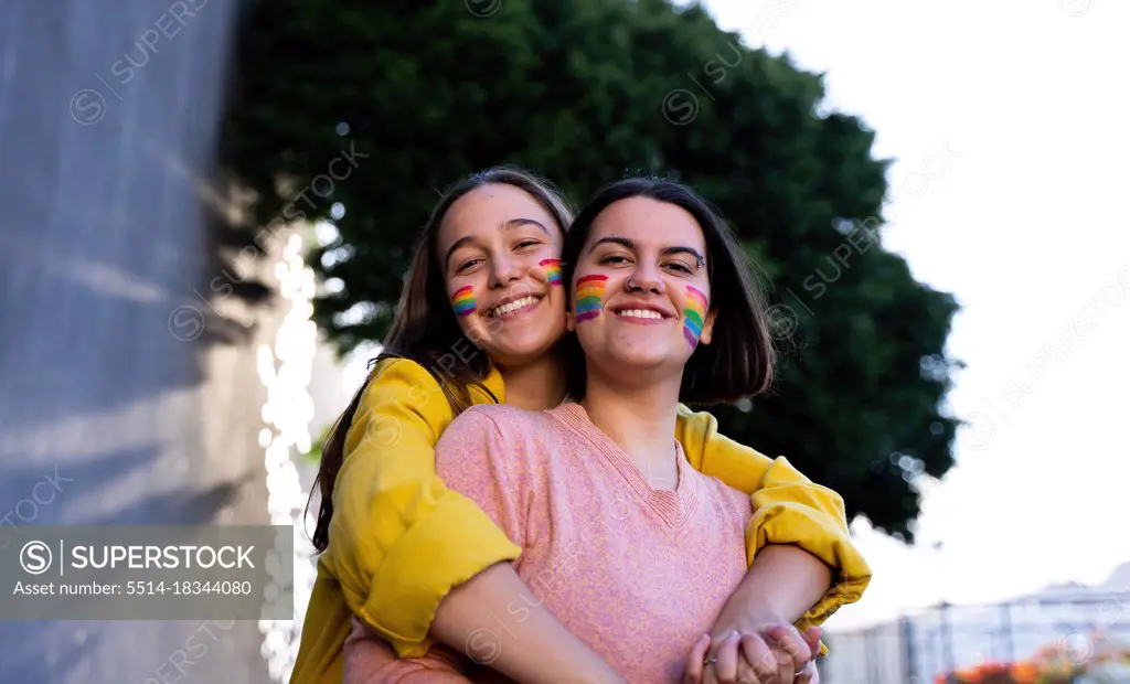 beautiful lesbian couple having fun in the street with a lgtb flag