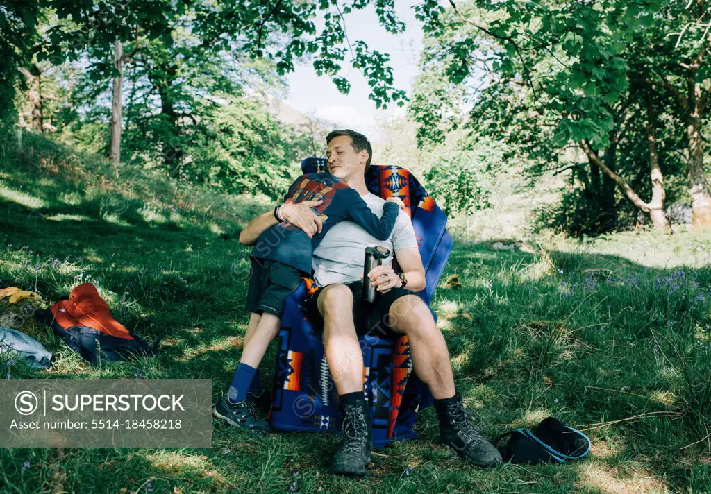 dad hugging his son whilst camping in the sunshine on vacation