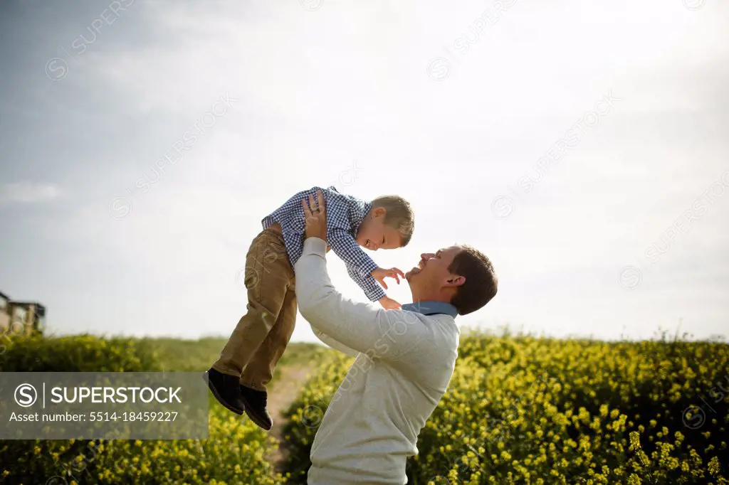 Dad Lifting Son Up in Wildflower Field