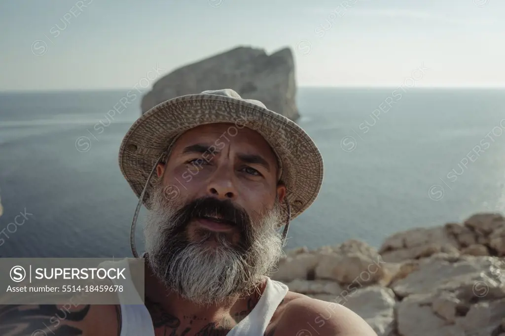 Bearded man with hat taking selfie with his camera