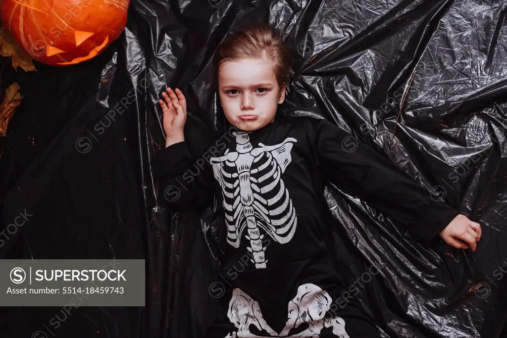 Kid boy at 5 wearing a skeleton costume at the Halloween party at home