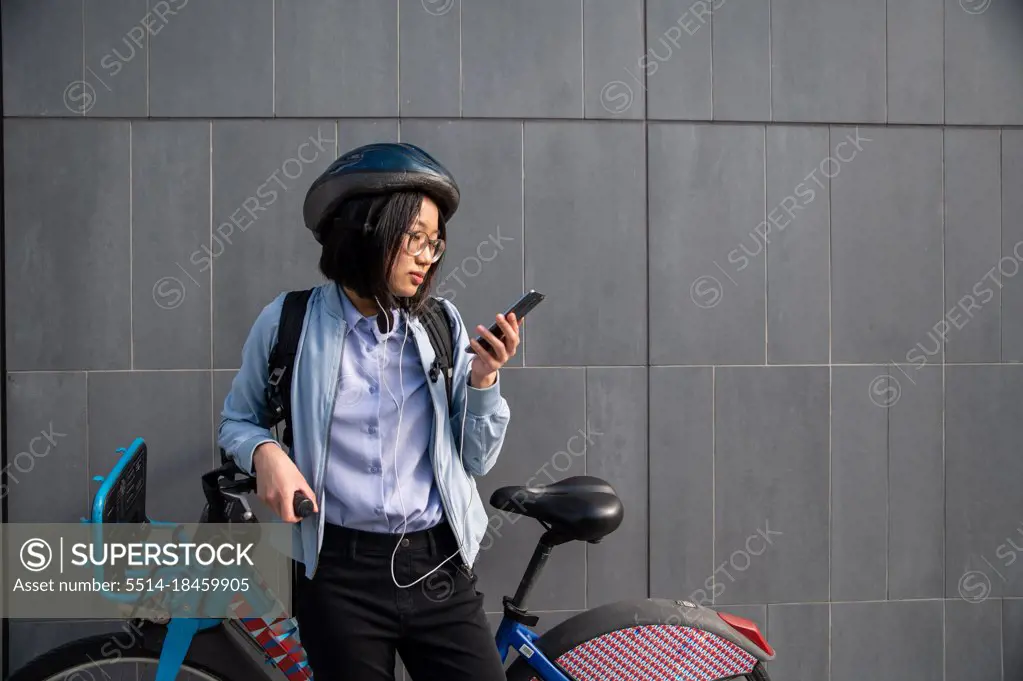 Young person looking at cell phone with urban bike rental