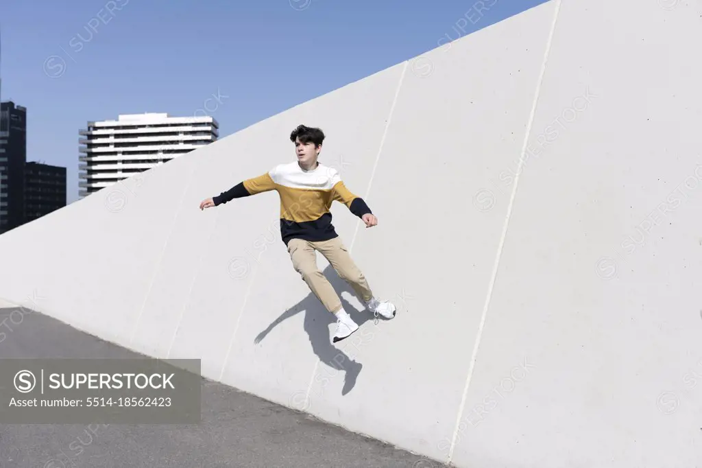 Young man jumping on the urban wall background