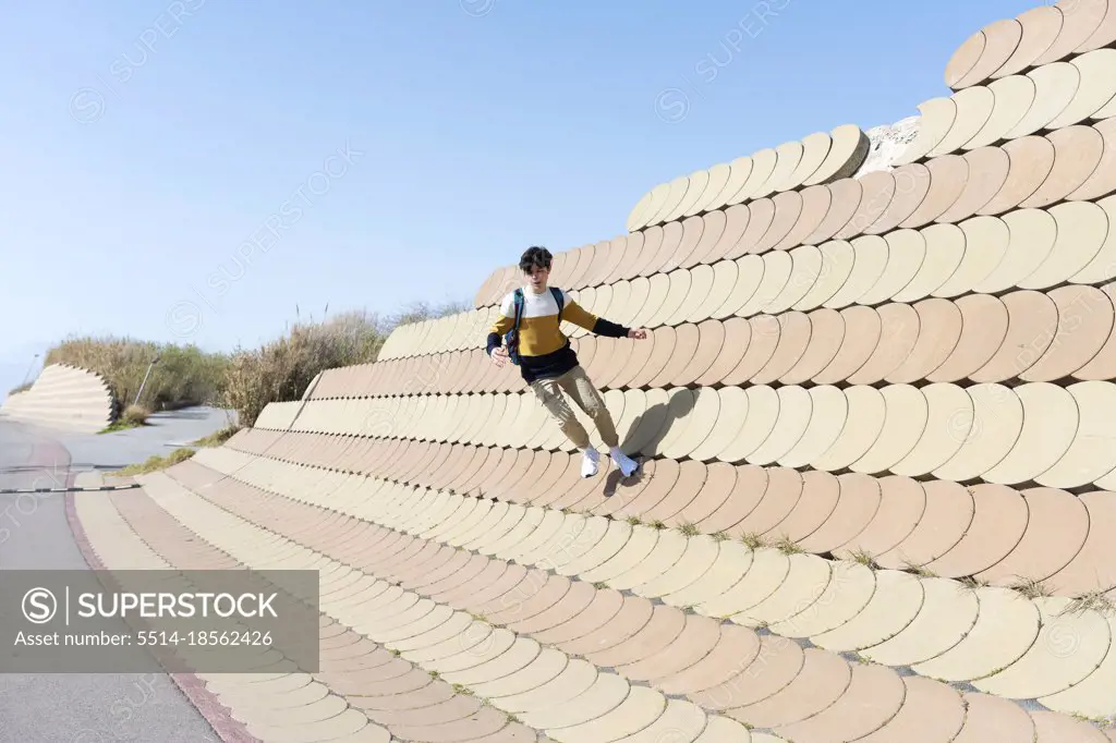 Young man jumping on the urban wall background