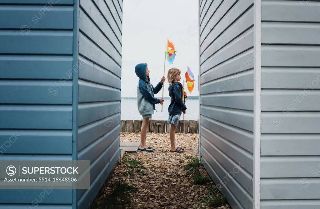 kids playing with windmills at the beach next to beach huts