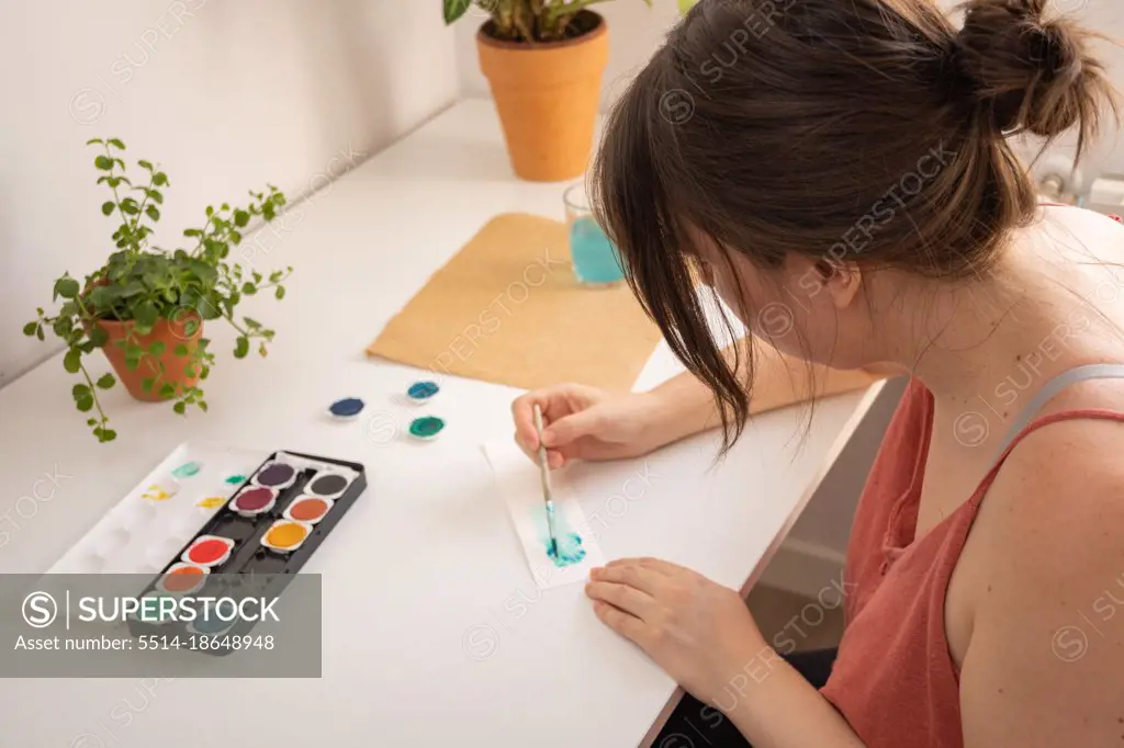 woman painting with watercolors in her studio at home