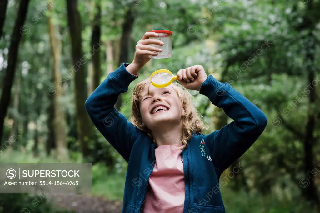 girl looking through a magnifying glass at bugs in the forest