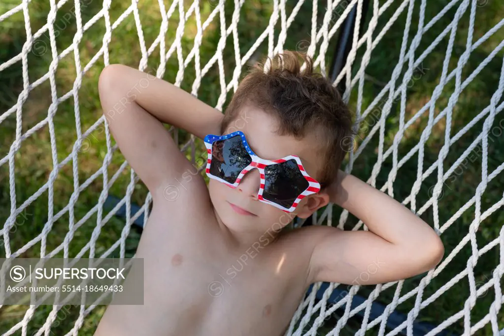 tight shot of a boy with a dreamy expression relaxing in a hammock