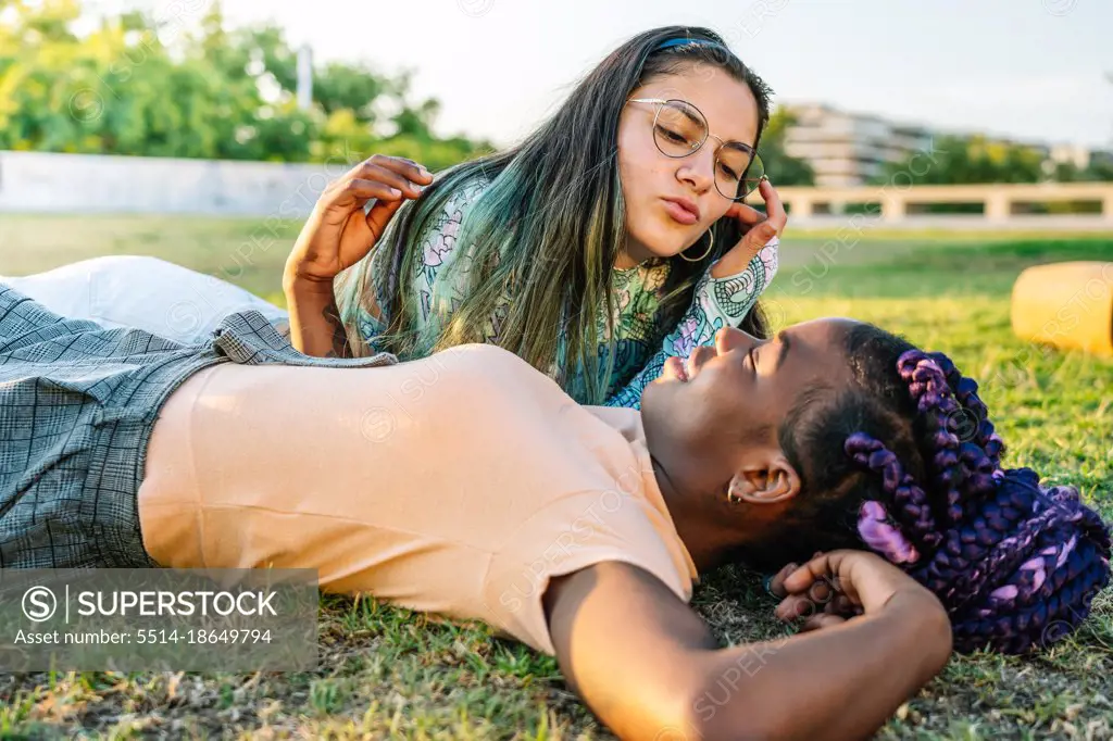 Multiracial female couple  lying on the grass. Lesbian couple