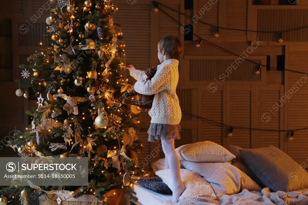 Side view of a child decorating a Christmas tree.