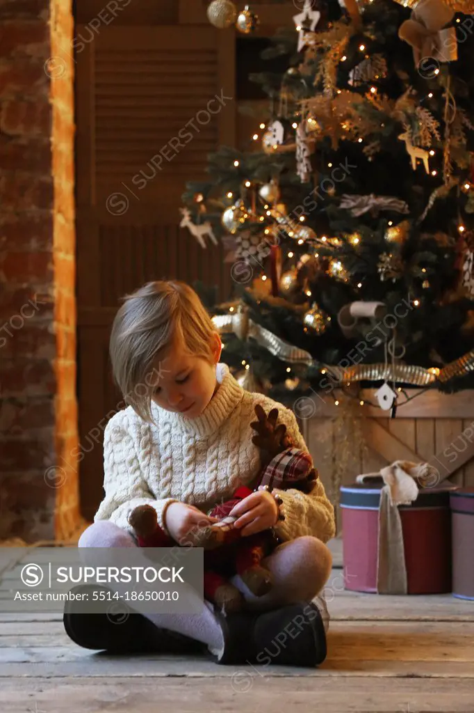 The child hugs a soft toy while sitting in warm clothes.