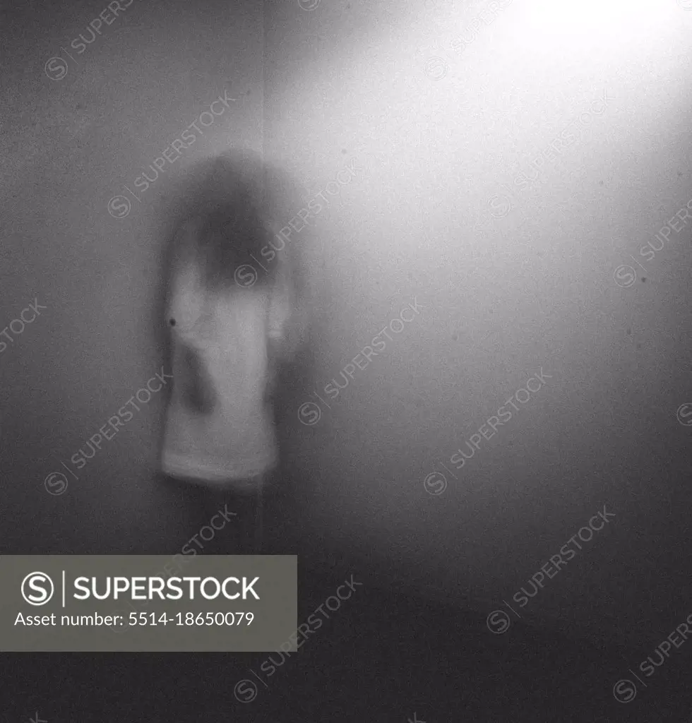 Ghost girl in white nightgown standing in corner of room at home