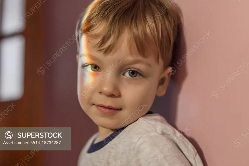 Portrait of a toddler boy with rainbow light on his right eye 