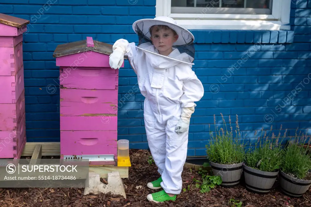 Portrait of a child beekeeper leaning on his hives