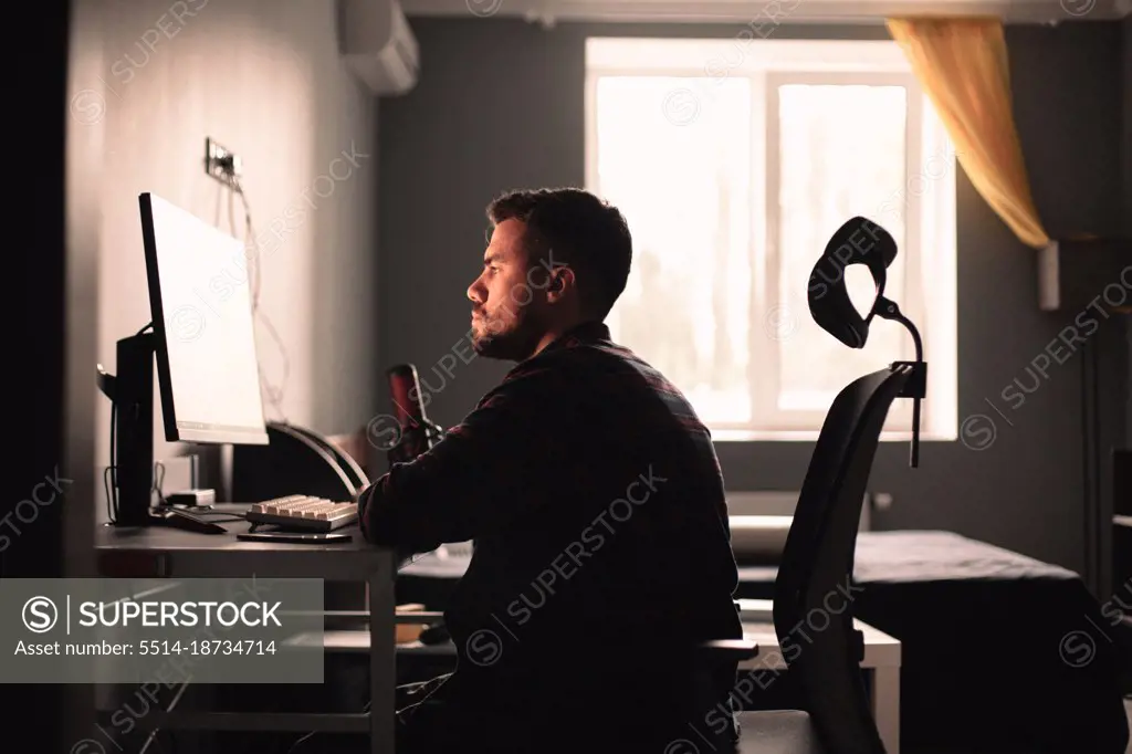 Man sitting at desk working on computer at home