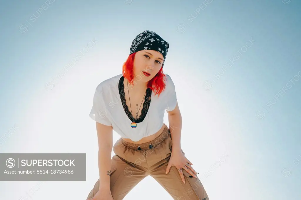 Portrait of a young woman with red hair and a necklace with lgbt flag