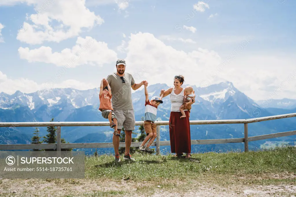 Young family having fun with kids in the Alps in summer