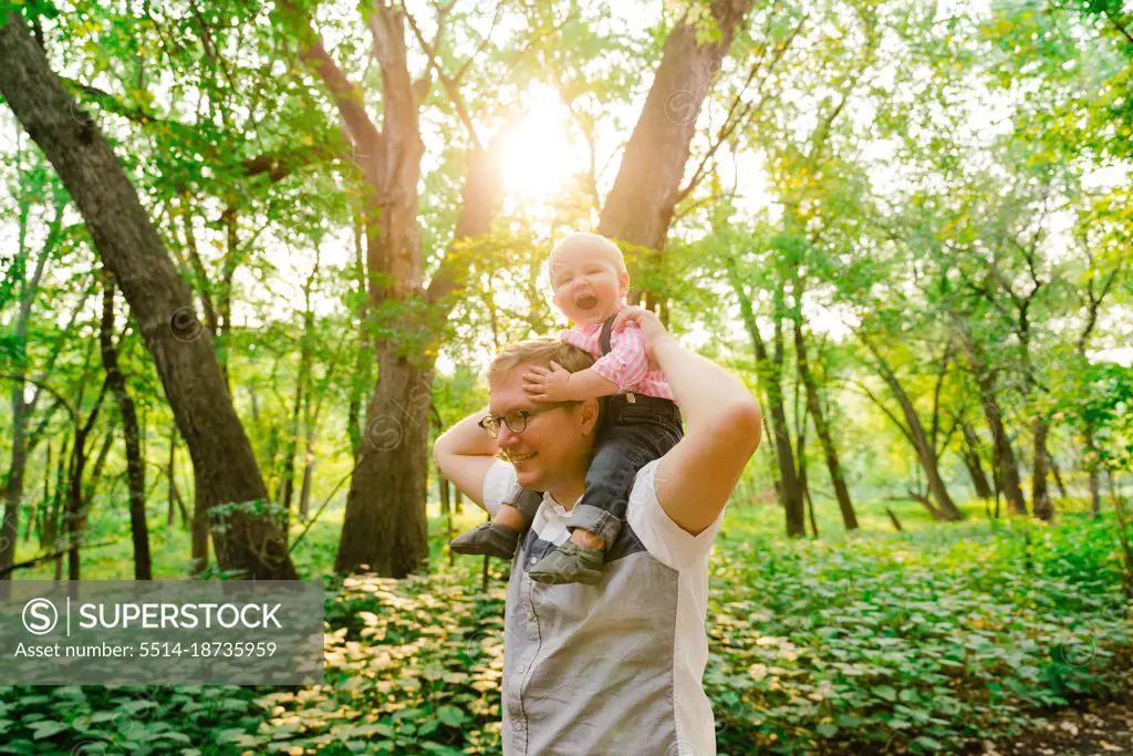 Lifestyle portrait of a baby riding on his dad's shoulders