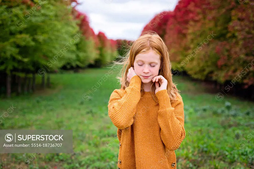 Happy tween girl surrounded by fall color trees.