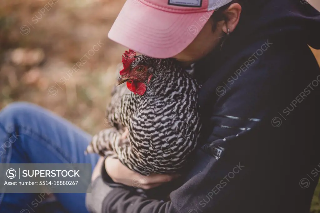 Teen girl holding chicken and kissing her