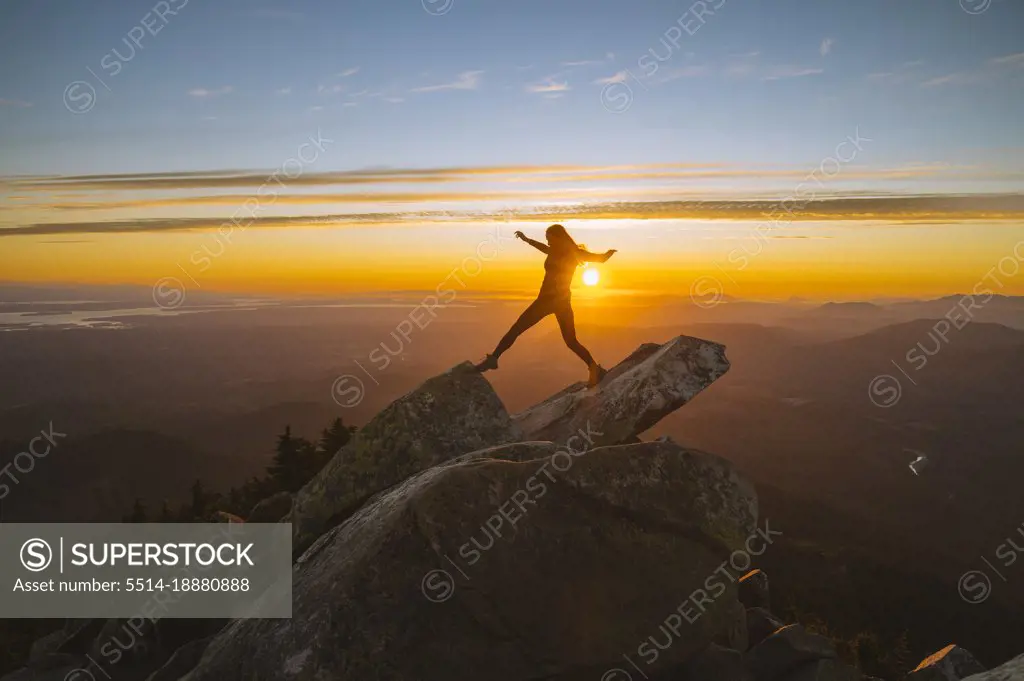 Silhouette of a woman on a mountain peak at sunset