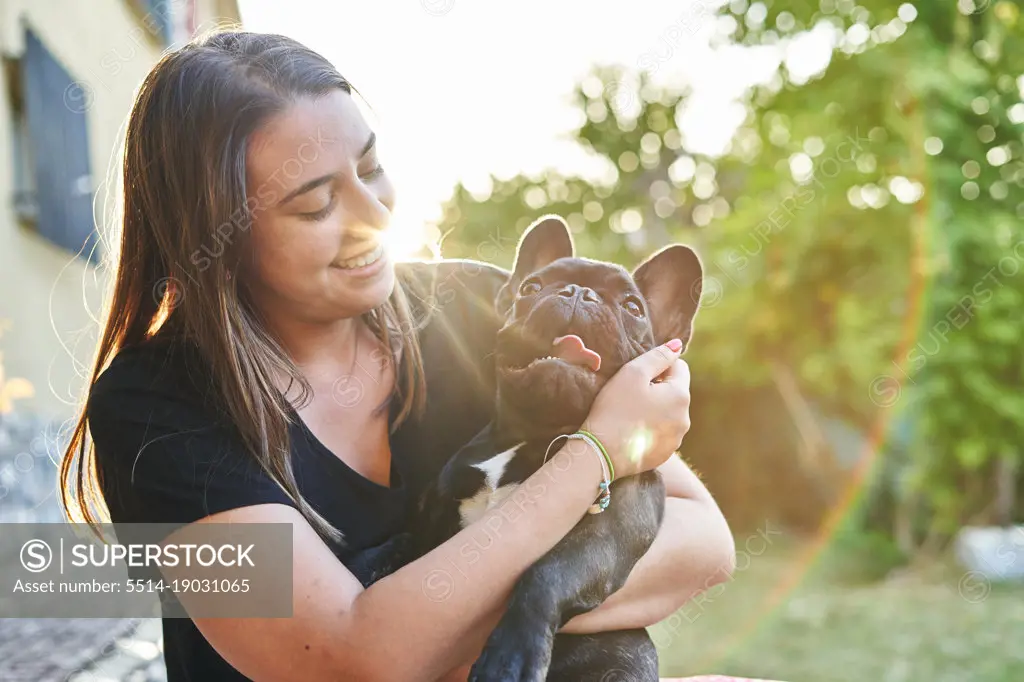 Young woman and her dog in the garden at sunset