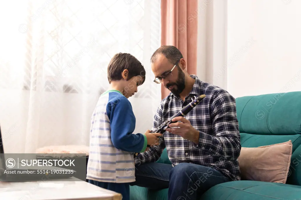 Father teaching his son to play the clarinet in the living room