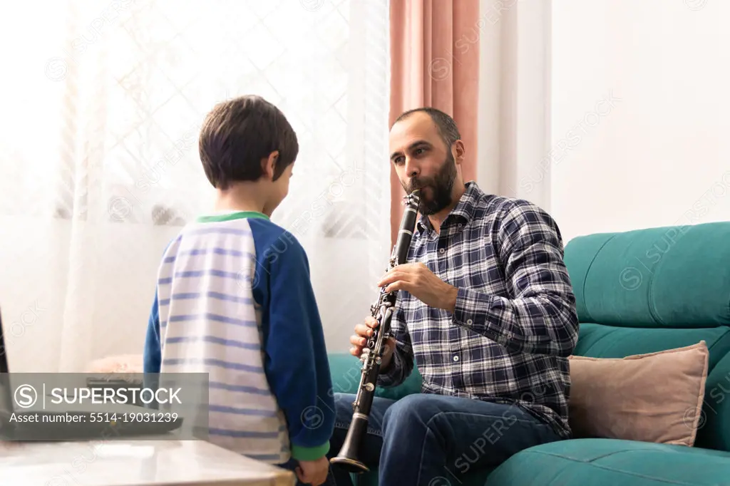 Father teaching his son to play the clarinet in the living room