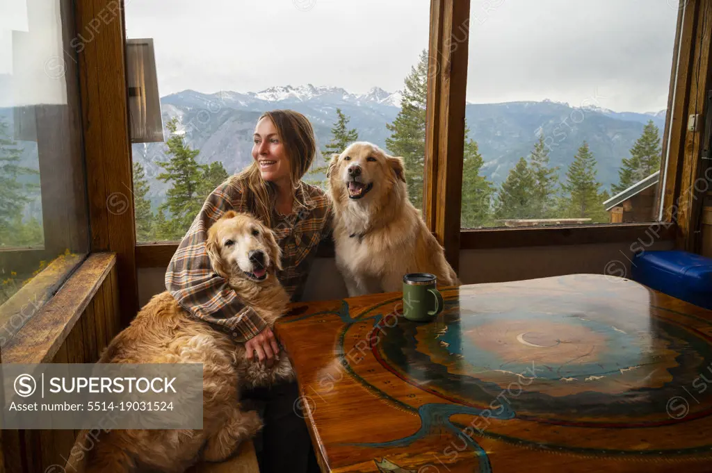 Female with dogs having coffee in a mountain cabin