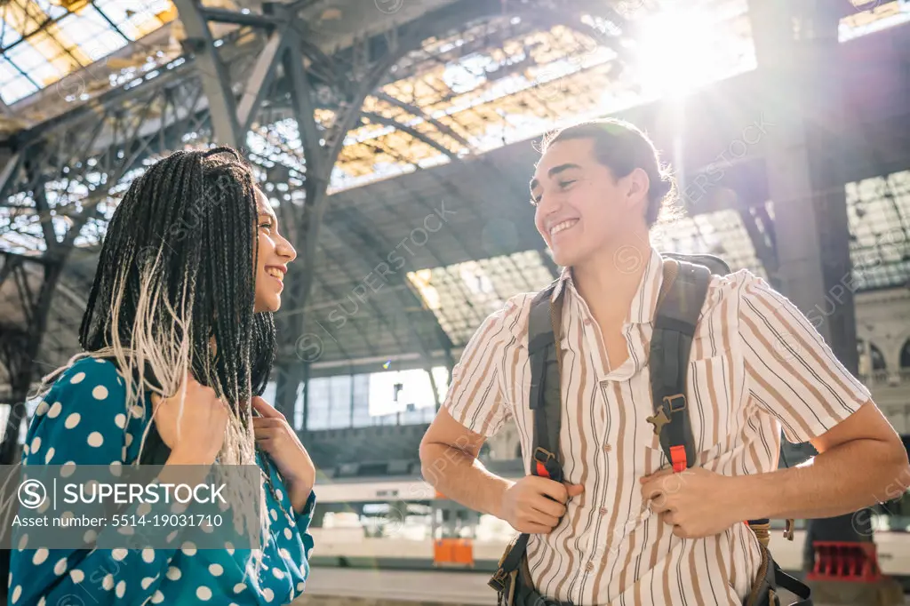 Cheerful diverse couple on railroad station