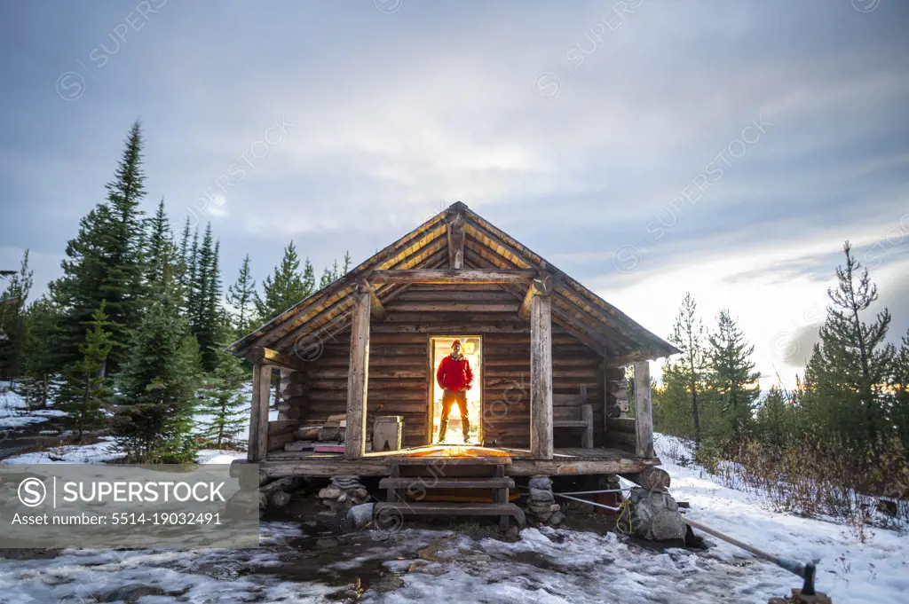 Male standing in doorway of Snow Peak Cabin in national forest