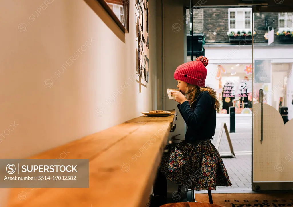 child sitting in a cafe in London enjoying a hot chocolate