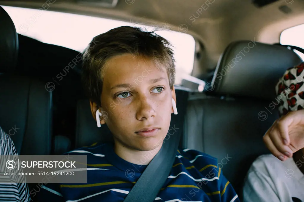 Bored Teen Boy Stuck in Backseat with Earphones on a Roadtrip